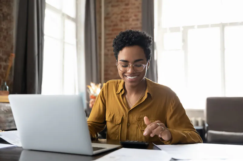 Joven afroamericana feliz con gafas organizando con éxito sus finanzas con un préstamo de capital privado