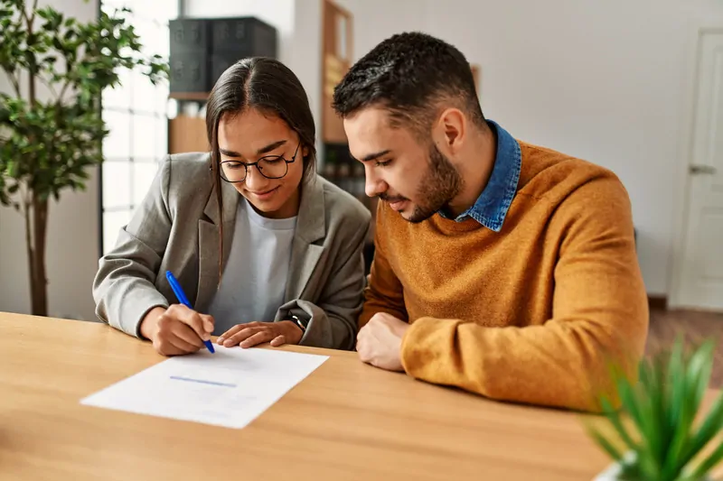 Pareja joven firmando un prestamo para refinanciar deudas con asnef